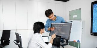 Dwóch młodych specjalistów pracuje wspólnie nad kodem w biurze startupu