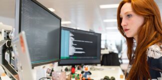 Inżynierka DevOps programuje na dwóch monitorach w nowoczesnym biurze