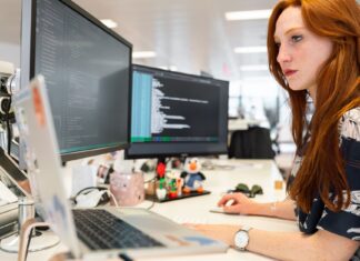 Inżynierka DevOps programuje na dwóch monitorach w nowoczesnym biurze