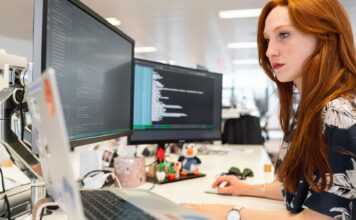 Inżynierka DevOps programuje na dwóch monitorach w nowoczesnym biurze