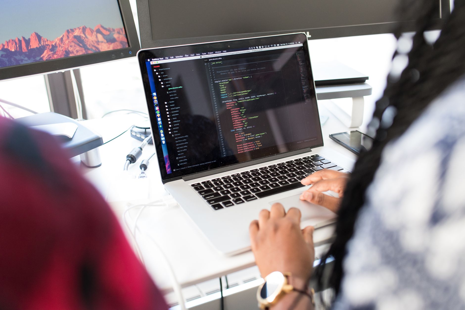 Kobieta programująca na laptopie z Linuxem przy biurku z kilkoma monitorami