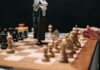 Historia sztucznej inteligencji: od prostych reguł do modeli generatywnych Ramię robota grające w szachy z człowiekiem, symbol rozwoju sztucznej inteligenc