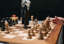 Historia sztucznej inteligencji: od prostych reguł do modeli generatywnych Ramię robota grające w szachy z człowiekiem, symbol rozwoju sztucznej inteligenc