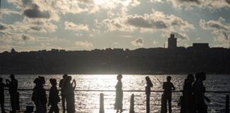 Spacerowicze nad wodą o zachodzie słońca z panoramą miasta w tle