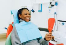 Uśmiechnięta pacjentka z lusterkiem podczas kontroli u dentysty