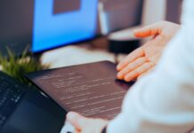 Najlepsze narzędzia AI dla programistów w 2025 roku Programista analizujący kod na tablecie w nowoczesnym biurze