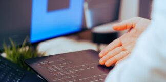 Najlepsze narzędzia AI dla programistów w 2025 roku Programista analizujący kod na tablecie w nowoczesnym biurze