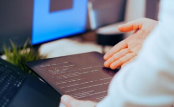 Najlepsze narzędzia AI dla programistów w 2025 roku Programista analizujący kod na tablecie w nowoczesnym biurze