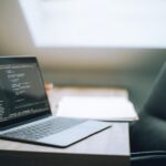 Otwarty laptop z kodem na biurku w nowoczesnym jasnym biurze