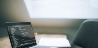 Otwarty laptop z kodem na biurku w nowoczesnym jasnym biurze
