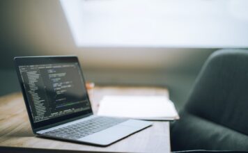 Otwarty laptop z kodem na biurku w nowoczesnym jasnym biurze