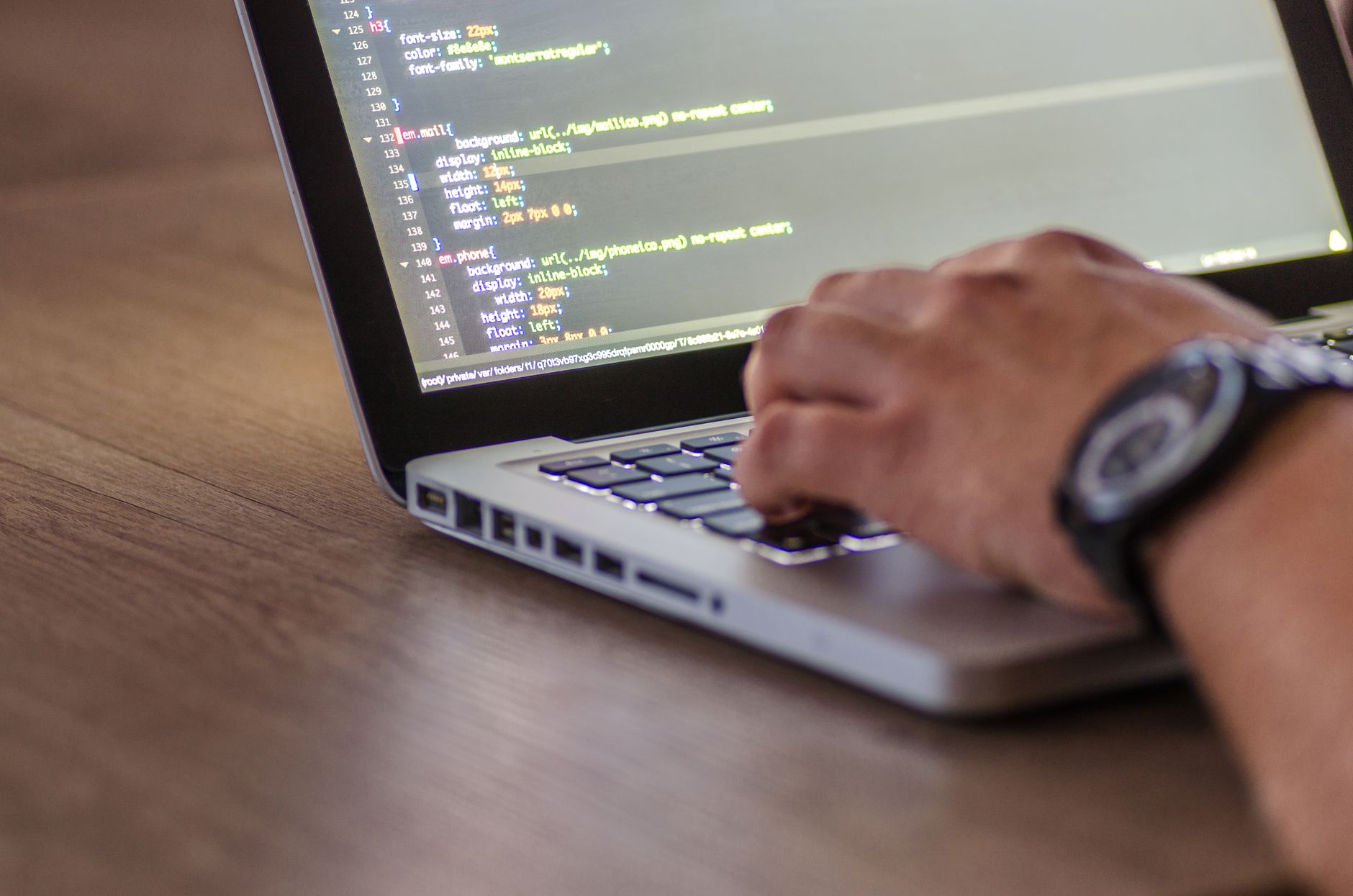Zbliżenie na dłonie programisty kodującego na laptopie